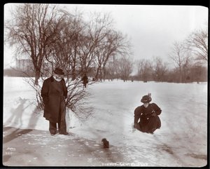 Vista de una mujer alimentando a una ardilla mientras un hombre observa en la nieve en Central Park, Nueva York, 1898